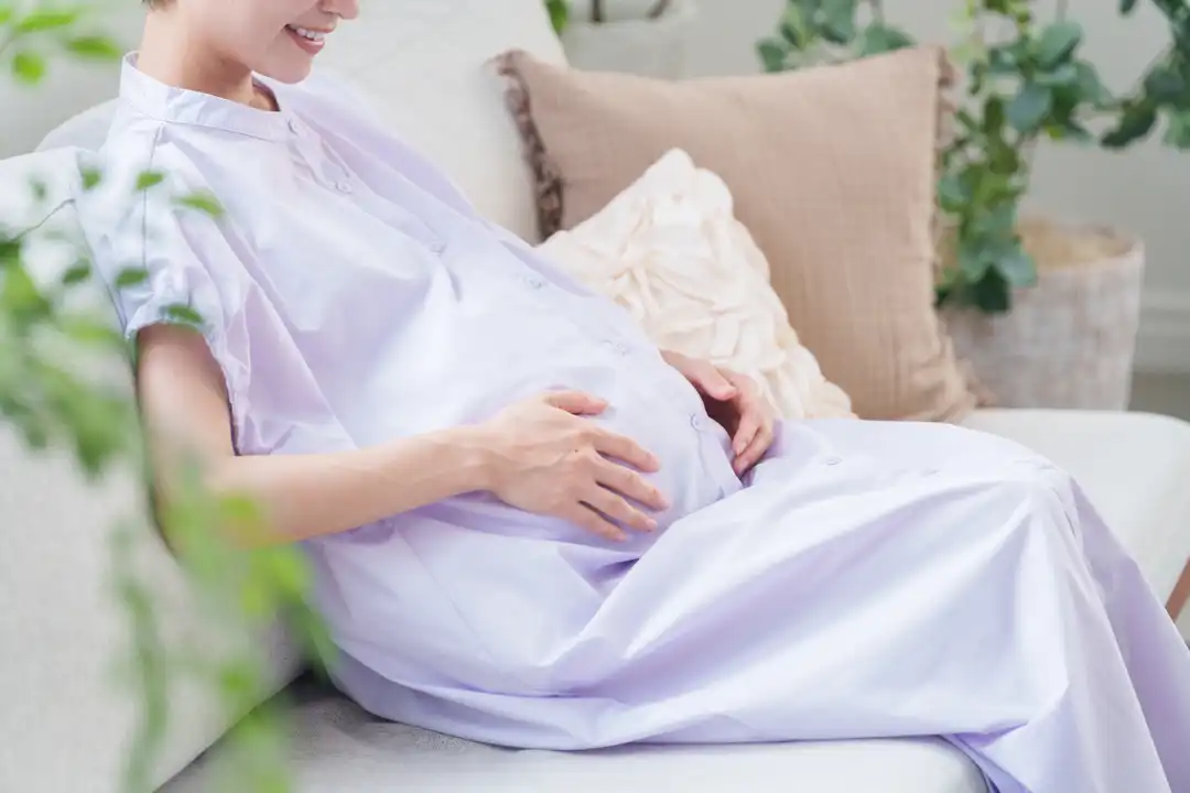Pregnant woman smiling and touching her belly